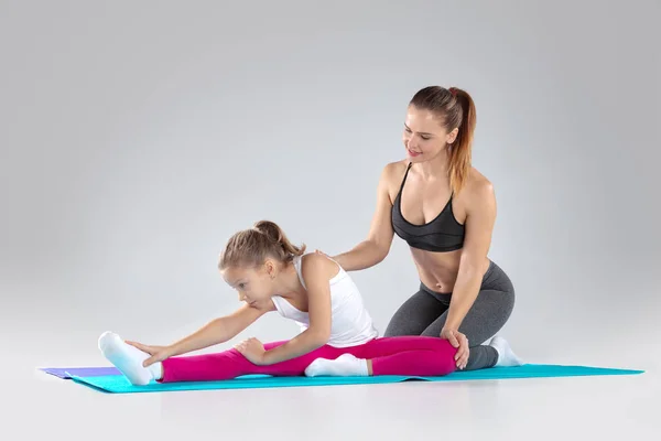 Mujer fitness y su hija están haciendo ejercicios en esteras — Foto de Stock
