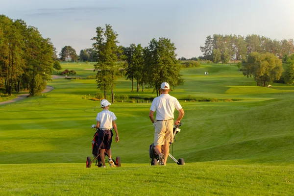 Hombre con su hijo golfistas caminando en el campo de golf — Foto de Stock