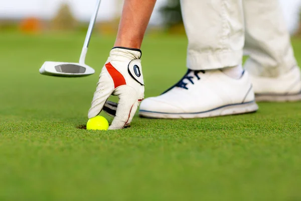 Mão masculina está colocando uma bola do buraco de golfe — Fotografia de Stock