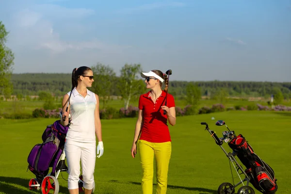 Dos mujeres guapas golfistas caminando en el campo de golf —  Fotos de Stock