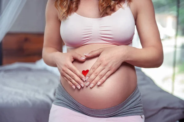 Беременная женщина трогает живот крупным планом. — стоковое фото