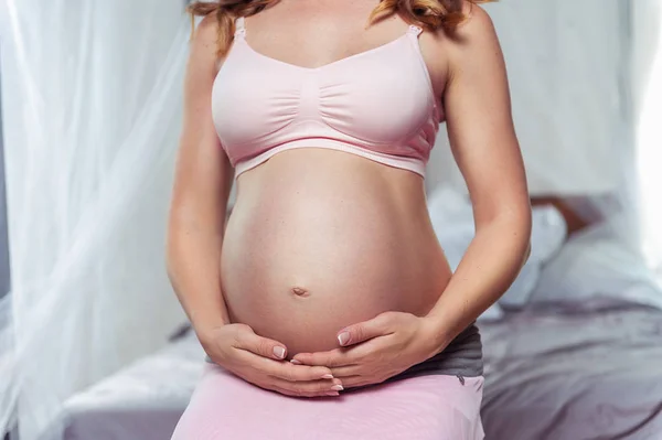 Беременная женщина трогает живот крупным планом. — стоковое фото