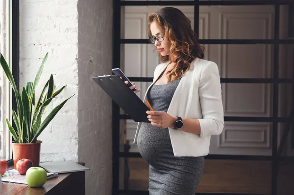 Embarazada madura mujer de negocios trabajando en la oficina — Foto de Stock