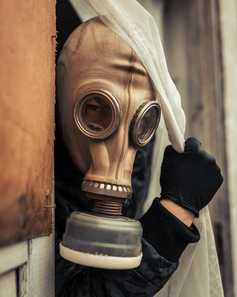 Man in a full-face protective mask walking through a transparent courtain, a military gas mask with a wilt box. Respiratory protection from harmful substances, chemical and biological weapons, corrosive chemicals.