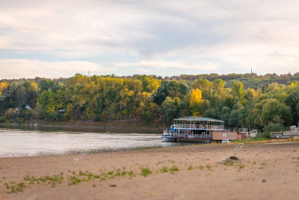 Passenger boats pick up tourists in the docks on a river's shore in the nature. trees in the background