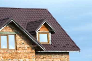 Yeni tugla ev kahverengi shingle çatı ve Plastik tavan windows parlak mavi gökyüzü arka plan üzerinde yakın çekim detayını. Gayrimenkul ve profesyonelce yapılan iş kavramı.