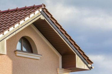 Yeni büyük ferah modern ev kırmızı çatılı, küçük yuvarlak tavan pencere, duvar ve parlak mavi gökyüzü arka plan kırmızı kiremit shingled tepesinde. Profesyonelce yapılan inşaat iş kavramı.