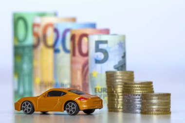 Bulanık satır yüz, elli, yirmi, on ve beş yeni euro banknot ve madeni paralarla sarı oyuncak pahalı spor araba yığını haddelenmiş. Finansal refah, araç satış ve satınalma sembolü.