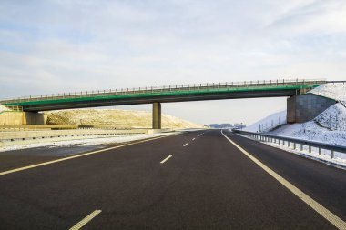 Ufuk yüksek köprü dönüm değil uzak orman geçmiş gün altında uzanan Modern geniş düz boş asfalt karayolu. Hız, rahat yolculuk ve profesyonel yol kavram bina.