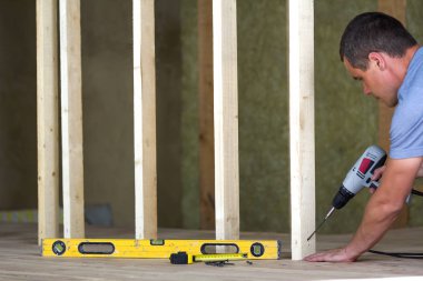 İç tavan arası Oda meşe döşeme altında yeniden yapılanma ile izole. Genç profesyonel alt düzey ve gelecekteki duvarlar için ahşap çerçeve yükleme tornavida kullanır. Yenileme ve iyileştirme kavramı.