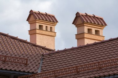 Yeni geniş modern ve büyük ev kırmızı çatı shingled, iki yüksek bacalar, sıvalı duvarlar kar koruma çiti parlak mavi gökyüzü arka plan karşı tepesinde. Profesyonelce yapılan inşaat kavramı.