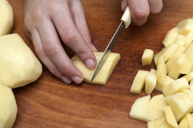 Kadın eli mutfak ahşap tahta üzerinde patates Dilimleme bir bıçak kesim ile. Sağlıklı beslenme ve yaşam tarzı. Yakın çekim yukarıda görüntülemek