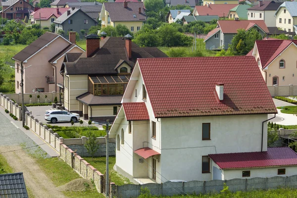 Sakin yerleşim bölgesinde yeni pahalı iki katlı evler tuğla çit ve kiremit çatılar ve döşeli bakımlı bahçesinde garaj kapısı önünde park edilmiş beyaz spor araba ile. Lüks ve refah kavramı.