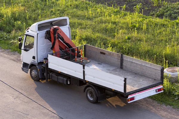 Vinç ülke yeşil çimenli yol kenarında park etmiş güneş beyaz boş hidrolik kamyon monte edilmiş yaktı. Modern gelişmiş ulaşım araç inşaat, malları teslim, yükleme ve boşaltma kavramı.