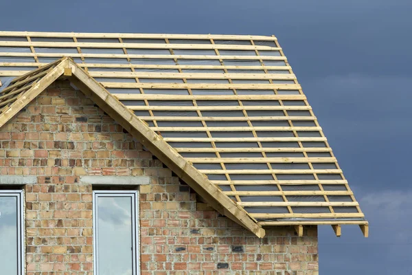 Yeni tugla evi iki dar Plastik tavan pencereleri ve ahşap çatı çerçeve yapım aşamasında koyu mavi gökyüzü arka plan üzerinde yakın çekim detayını. Gayrimenkul ve profesyonel iş kavramı.