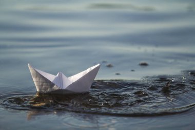 Basit küçük beyaz origami kağıt tekne mavi temiz nehir veya deniz su parlak yaz göğün altında yüzen Close-up. Doğa, özgürlük, düşler ve fantasies kavramının güzellik.