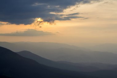 Geniş panorama, muhteşem manzarası, Güneş doğmadan önce karanlık bulutlar ve hafif pembe gökyüzü altında şafakta sabah sis yeşil Karpat Dağları ile kaplı. Güzellik, Doğa, turizm ve seyahat kavramı.