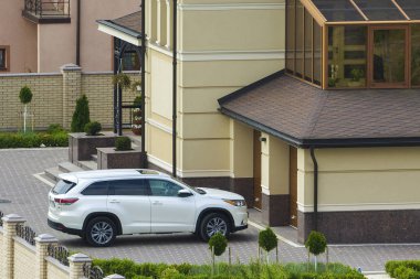 Yeni pahalı beyaz spor araba Honda garaj kapısı önünde park etmiş yeşil çim, Dekoratif ağaçlar ve tuğla çit büyük iki hikaye yazlık bakımlı bahçesinde açtı. Lüks ve refah kavramı.