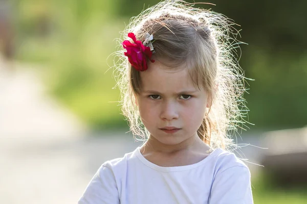 素敵な灰色の目と髪に赤いバラと不機嫌そうなかなり小さいブロンドの女の子は怒っているとカメラの不満です 子供のかんしゃくと養育問題の概念 — ストック写真