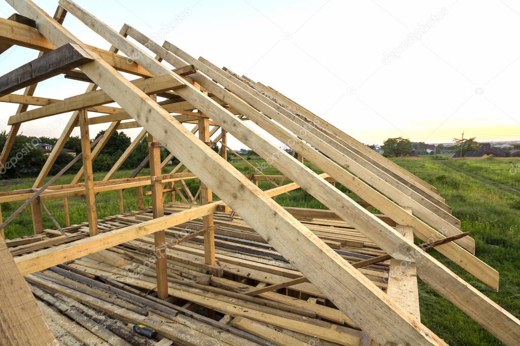 New wooden ecological house from natural materials under construction. Close-up detail of attic roof frame against clear sky from inside. Building, roofing, construction and renovation concept.