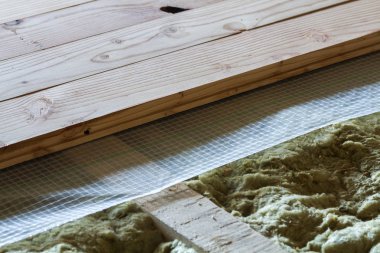 Installation of new floor of wooden natural planks and mineral wool insulation for isolation and keeping warmth. Construction, renovation, warm comfortable house concept. clipart