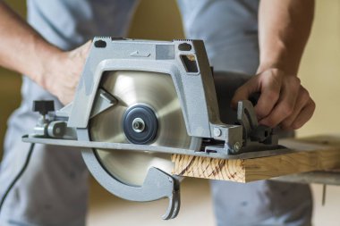 Yakın çekim yeni parlak modern güçlü dairesel keskin elektrik kullanarak kas marangoz el için zor ahşap tahta kesme gördüm. İnşaat ve yapı kavramı için profesyonel araçlar.