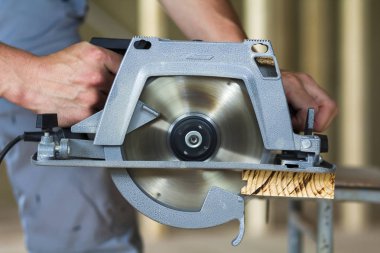 Yakın çekim yeni parlak modern güçlü dairesel keskin elektrik kullanarak kas marangoz el için zor ahşap tahta kesme gördüm. İnşaat ve yapı kavramı için profesyonel araçlar.