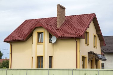 Yeni sarı iki katlı konut yazlık shingle çatı, ön sundurma, plastik pencere, yüksek bacalar, mavi gökyüzü arka plan üzerinde balkon ile. Gayrimenkul mülkiyet, mimari ve refah kavramı.