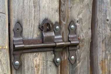 Güneş eski kaba ahşap plakalar ev kapı veya ahır kapısı demir paslı slayt cıvata kilit ile yapılan tarafından Close-up yaktı. Eskimiş teknoloji, güvenlik, güvenlik ve hırsız kavramı koruma.