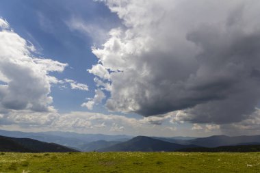 Sabah güneş geniş yeşil vadi tarafından yaktı, tepeler orman ve parlak mavi yaz gökyüzü ve beyaz bulutlar altında uzak sisli dağlar ile kaplı. Güzellik, Doğa, turizm ve seyahat kavramı.