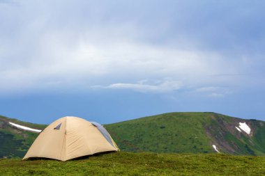 Yaz parlak güneşli bir günde. Küçük turistik çadır uzak Sisli Yeşil dağların altında açık mavi bulutsuz gökyüzü arka plan üzerinde çimenli Vadisi üzerinde. Turizm, hiking, kamp ve doğa kavramının güzellik.