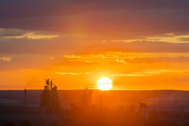Karanlık siluetleri modern çimento fabrikası ve güç istasyonu parlak büyük beyaz ayarı veya dramatik sarı kırmızı gökyüzü arka plan güneşte yükselen yüksek binalar. Teknoloji, güzellik ve ekolojik sorunları.
