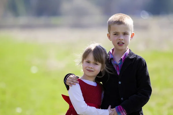 美丽的金发孩子的肖像与有趣的儿童牙齿在聪明的衣服站在一起在户外模糊的背景 哥哥拥抱妹妹 快乐粗心大意的童年概念 — 图库照片