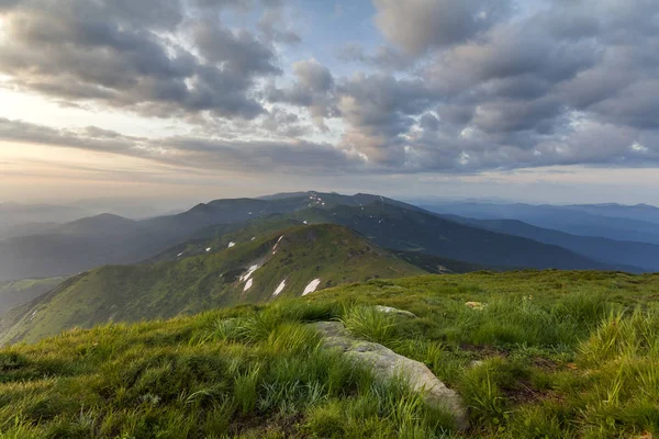 Geniş Yataklı güneş doğarken yaz. Parlak turuncu güneş mavi bulutlu gökyüzü büyük kaya ve uzak dağ ile yeşil çimenli tepeye üzerinde yükselterek sabah sis ile kaplı. Doğa kavramının güzellik.