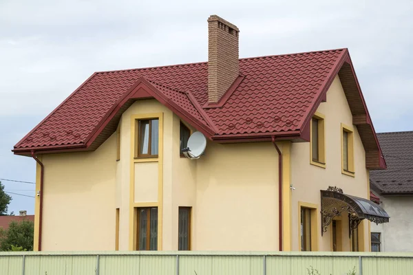 Yeni sarı iki katlı konut yazlık shingle çatı, ön sundurma, plastik pencere, yüksek bacalar, mavi gökyüzü arka plan üzerinde balkon ile. Gayrimenkul mülkiyet, mimari ve refah kavramı.