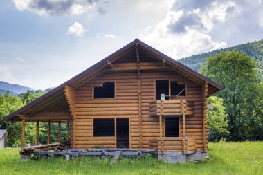Balkon, Teras, dik çatı yapım aşamasında ormanlık tepeler arka plan üzerinde otsu çayır üzerinde doğal malzemelerden yeni ahşap ekolojik yazlık. Eski gelenek ve modern bina kavramı.