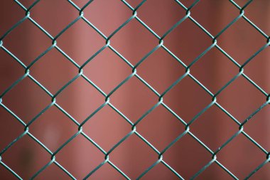 İzole boyalı basit geometrik siyah demir metal tel zincir bağlantı çit eon koyu kırmızı zemin Close-up. Çit, koruma ve muhafaza kavramı.