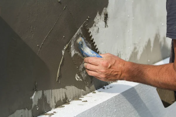 こてに接着剤を適用する労働者の手の細部のクローズ アップは漆喰白い家壁をポリウレタン フォーム断熱材です 近代的な技術 ミネラル ウールのコンセプトの代替 — ストック写真