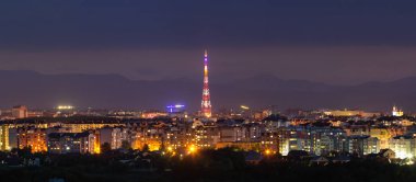 Geniş panorama, modern turistik Ivano-Frankivsk City, Ukrayna hava gece görünümü. Yüksek binalar, yüksek televizyon kulesi ve Karpat Dağları zemin üzerine yeşil banliyölerde parlak ışıkları sahne.