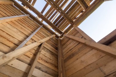 Yeni ahşap ev yapım aşamasında. Duvar ve çatı çerçevesinden içinde açık gökyüzü karşı yakın çekim. Doğal malzemelerin ekolojik rüya ev. Yapı, inşaat ve yenileme kavramı.