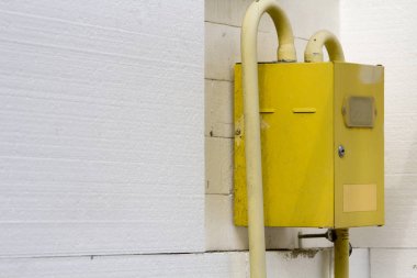 Ev duvar beyaz sert poliüretan styrophome sayfaları ile yalıtımlı köşesinde asılı borular bağlanma ile sarı gaz metre kutusunun yakın çekim. İnşaat, tadilat, enerji tasarrufu kavramı.