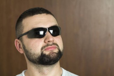 Portre yakışıklı siyah saçlı akıllı modern genç adam tür siyah arka plan üzerinde bulanık gülümseyen gözleri ve kısa saç kesimi bardaklarda sakallı. Gençlik ve güven kavramı.