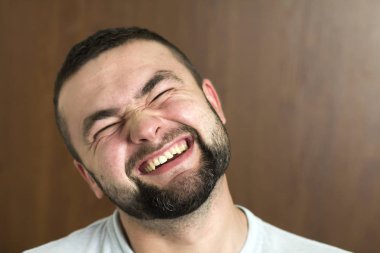 Portre yakışıklı siyah saçlı akıllı modern genç adam tür siyah arka plan üzerinde bulanık gülümseyen gözleri ve kısa saç kesimi bardaklarda sakallı. Gençlik ve güven kavramı.