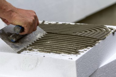 İşçi el ev yalıtımı için beyaz sert poliüretan köpük levha yapıştırıcı uygulayarak mala ile yakın çekim. Modern teknoloji, yenileme, profesyonel iş, mineral yün kavramı için alternatif.