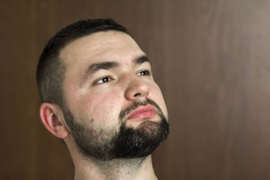 Yakışıklı portresi emin zeki modern fotojenik genç adam kısa saç kesimi ve siyah arka plan üzerinde bulanık ileriye düşünceli gözler sakallı. Gençlik ve güven kavramı.