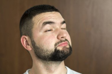 Portre yakışıklı siyah saçlı akıllı modern genç adam tür siyah arka plan üzerinde bulanık gülümseyen gözleri ve kısa saç kesimi bardaklarda sakallı. Gençlik ve güven kavramı.