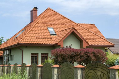 Shingle çatı, balkon, plastik tavan windows, taş döşeli Bahçe, yeşil çim ve parlak mavi gökyüzü arka plan üzerinde dekoratif çiçek açan ağaçlar ile yeni güzel tek katlı yazlık. Gayrimenkul mülkiyet kavramı.