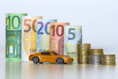 Bulanık satır yüz, elli, yirmi, on ve beş yeni euro banknot ve madeni paralarla sarı oyuncak pahalı spor araba yığını haddelenmiş. Finansal refah, araç satış ve satınalma sembolü.