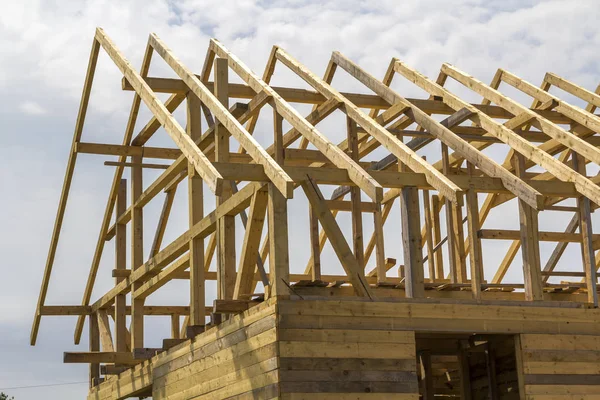 New wooden ecological house from natural materials under construction. Close-up detail of attic roof frame against clear sky. Building, roofing, construction and renovation concept.