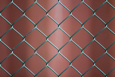 İzole boyalı basit geometrik siyah demir metal tel zincir bağlantı çit eon koyu kırmızı zemin Close-up. Çit, koruma ve muhafaza kavramı.